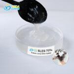 Close-up of SLES (Sodium Laureth Sulfate) liquid surfactant on transparent dish with spoon demonstrating viscosity and texture